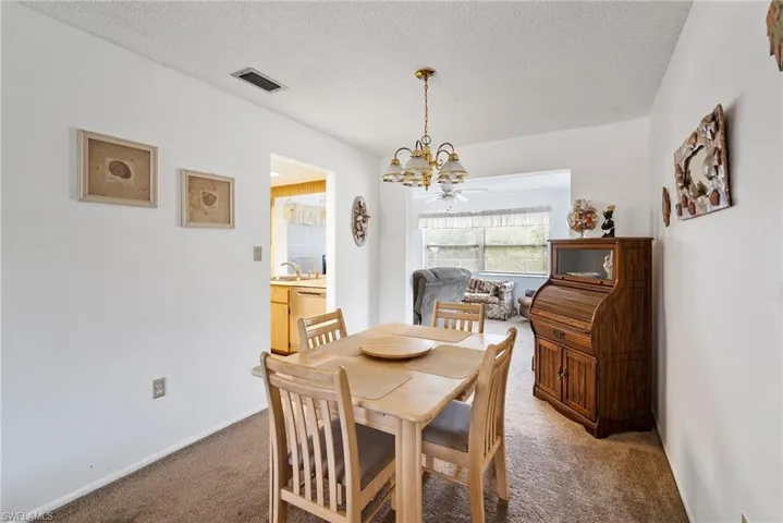 Dining area with a notable chandelier, sink, a textured ceiling, and carpet flooring