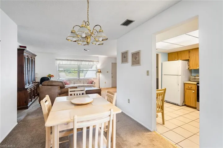 Dining space with a notable chandelier, a textured ceiling, and light tile floors