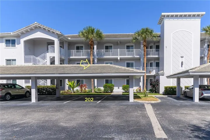 View of apartment building / complex featuring covered parking