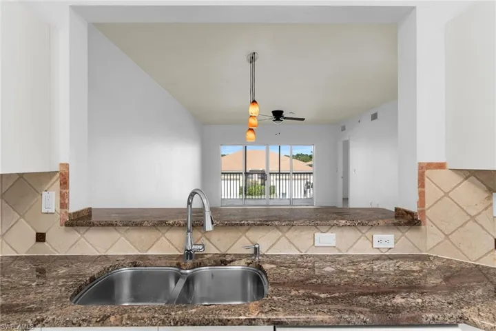Kitchen with tasteful backsplash, dark stone countertops, ceiling fan, and pendant lighting
