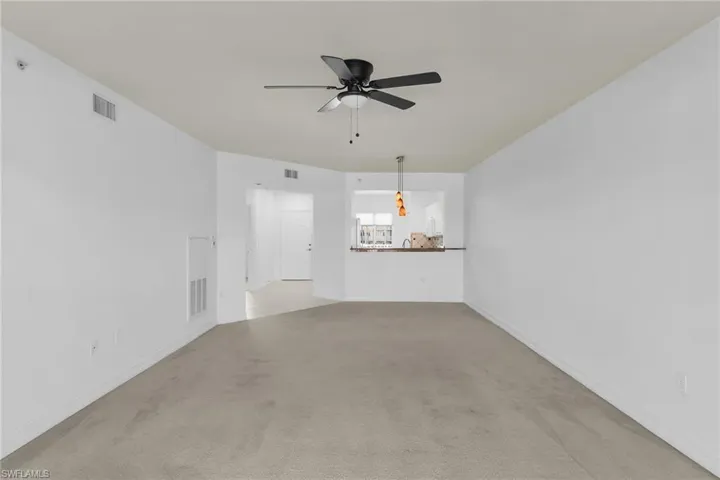 Unfurnished living room featuring ceiling fan and light carpet