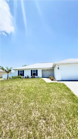 Single-story residence featuring a white exterior, dark window shutters, a white garage door, and a paver driveway