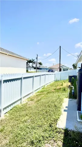 Side yard featuring a light-colored privacy fence and a concrete path