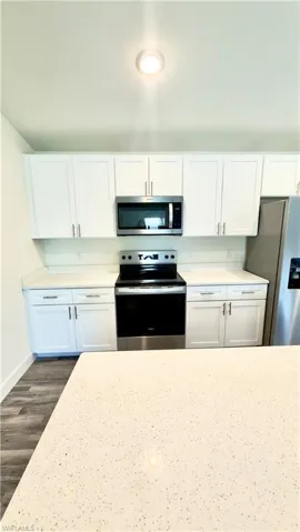 Kitchen featuring white upper and lower cabinetry, stainless steel appliances, and light-colored countertops