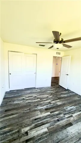 Room featuring wood-finish flooring, a ceiling fan with integrated lighting, and white walls