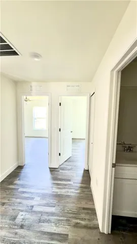 Hallway featuring wood-finish flooring, white walls, and recessed lighting
