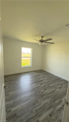 Room featuring wood-finish flooring, a window with exterior views, and a ceiling fan with integrated lighting