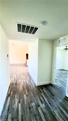 Expansive wood-finish flooring throughout, featuring a recessed ceiling light and an air return vent