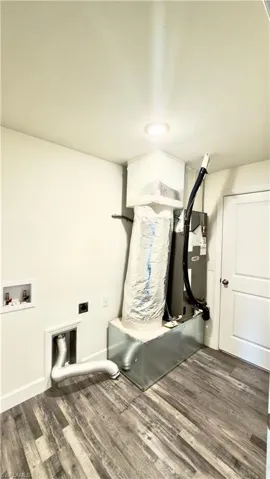 Utility area featuring wood-finish flooring, a white paneled door, and recessed lighting
