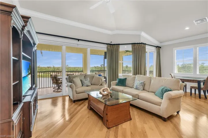 Living room featuring light hardwood / wood-style floors, vaulted ceiling, ceiling fan, and crown molding