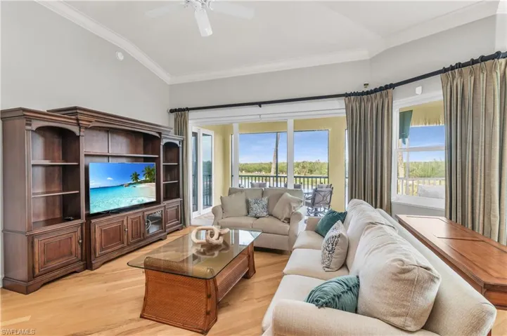 Living room featuring ceiling fan, light hardwood / wood-style floors, lofted ceiling, and ornamental molding