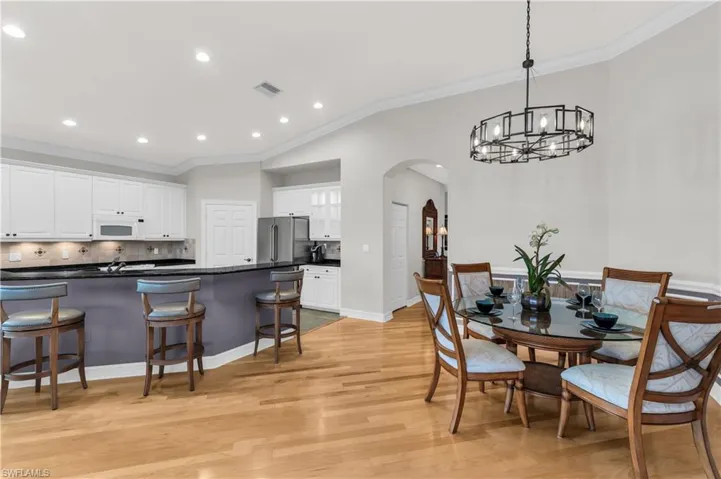 Dining space with vaulted ceiling, light wood-type flooring, ornamental molding, and an inviting chandelier