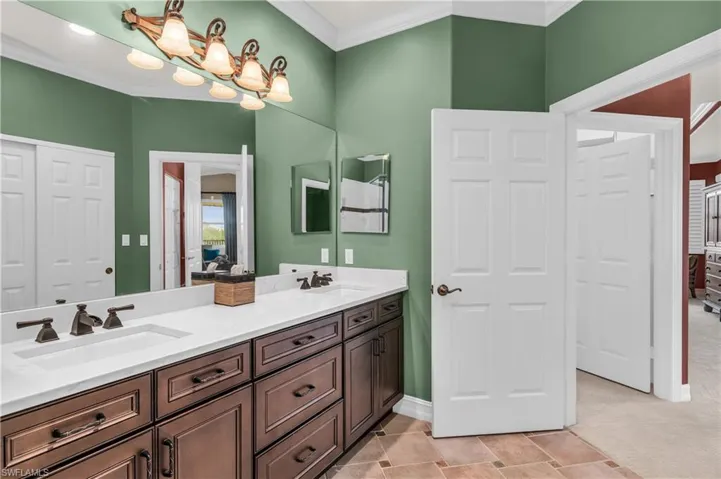 Bathroom featuring vanity, crown molding, and a notable chandelier