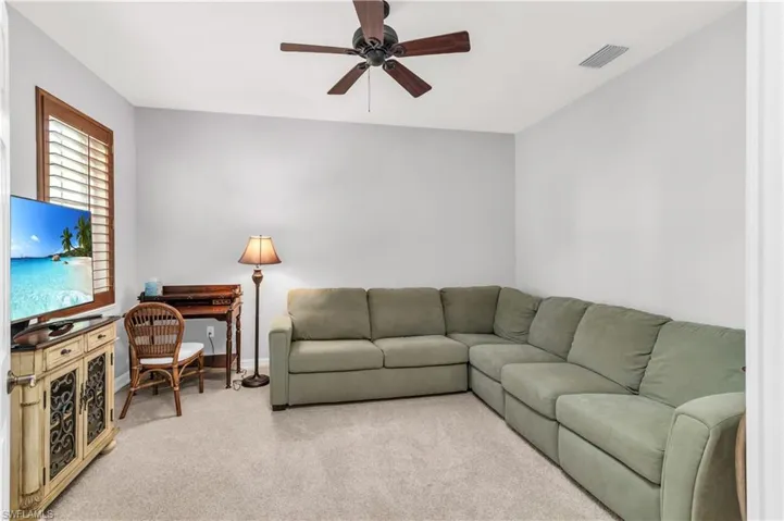 Carpeted living room with ceiling fan