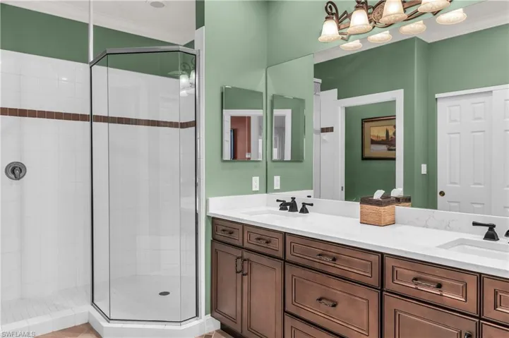 Bathroom with crown molding, a shower with door, and vanity