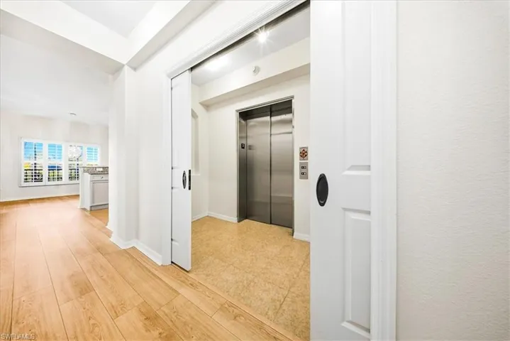 Hallway featuring elevator and baseboards