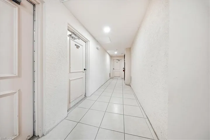 Hall with a textured wall, recessed lighting, and light tile patterned floors