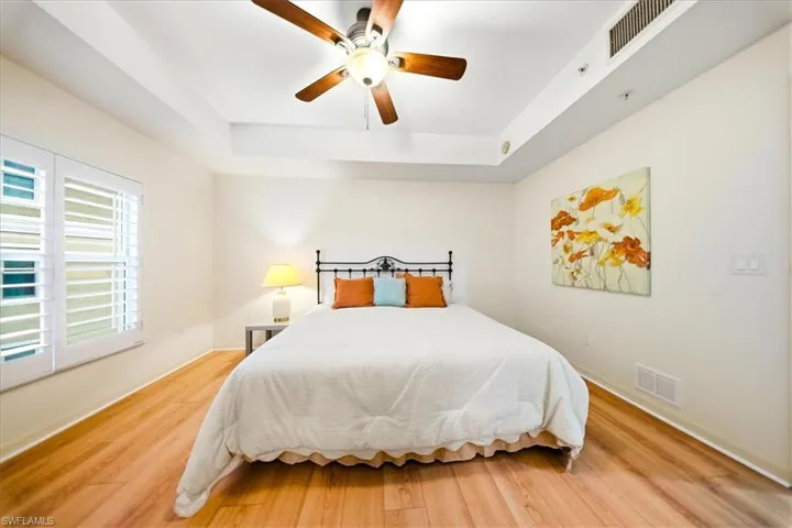 Bedroom featuring a tray ceiling, wood finished floors, and ceiling fan