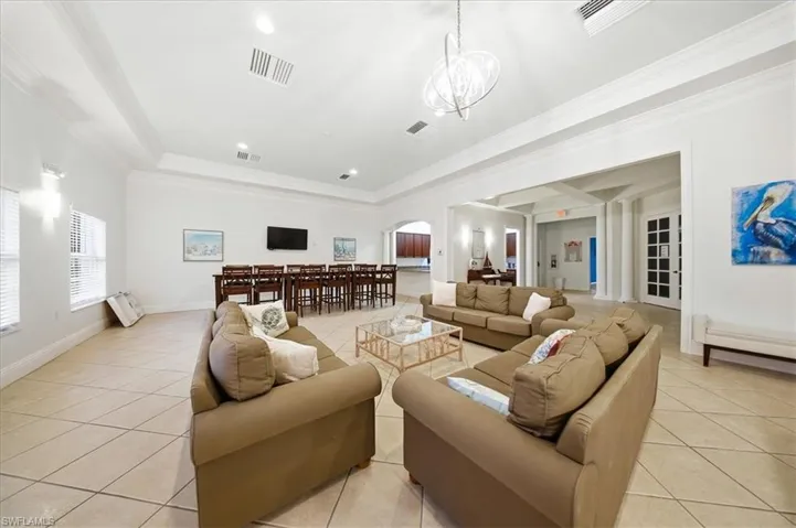 Living area featuring arched walkways, crown molding, light tile patterned floors, and recessed lighting