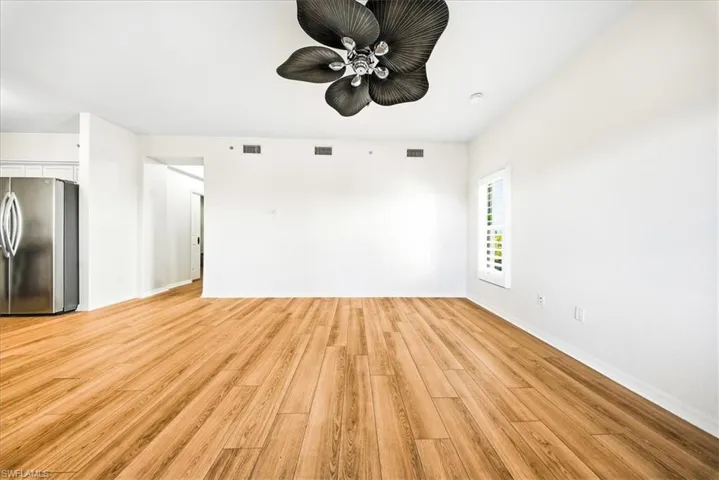 Unfurnished living room featuring light wood finished floors and baseboards