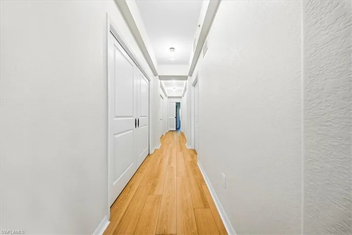 Hallway featuring light wood-style flooring and a textured wall