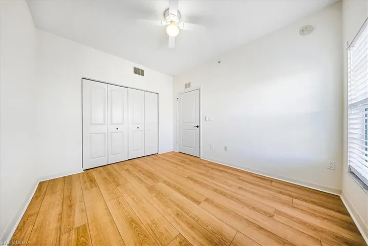 Unfurnished bedroom featuring light wood-style floors, a closet, a ceiling fan, and multiple windows