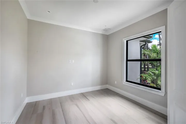 Empty room with ornamental molding and light hardwood / wood-style flooring