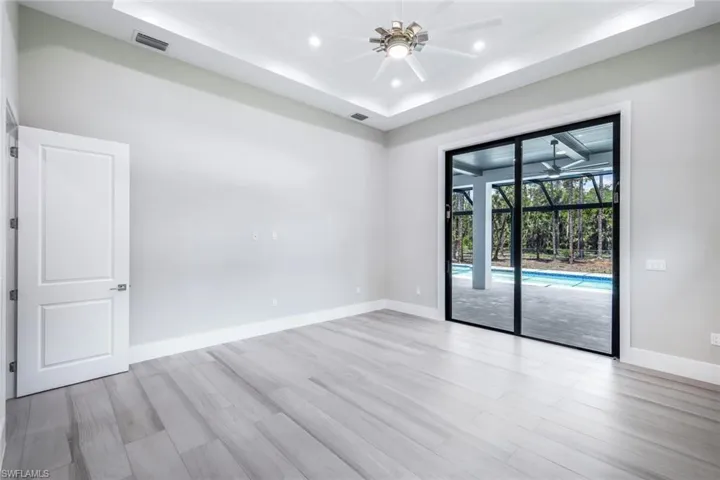 Spare room with light hardwood / wood-style floors, ceiling fan, and a raised ceiling