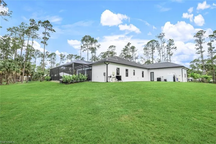 Rear view of property with a yard and glass enclosure