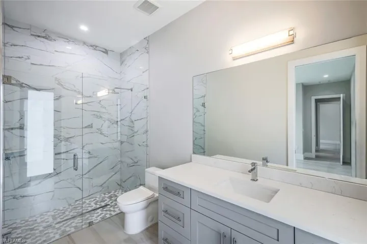 Bathroom featuring oversized vanity, toilet, and walk in shower