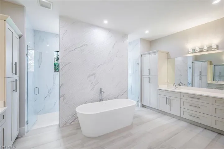 Bathroom featuring vanity with extensive cabinet space, independent shower and bath, tile walls, and tile flooring