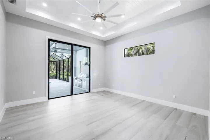 Unfurnished room with ceiling fan, a tray ceiling, and light hardwood / wood-style flooring