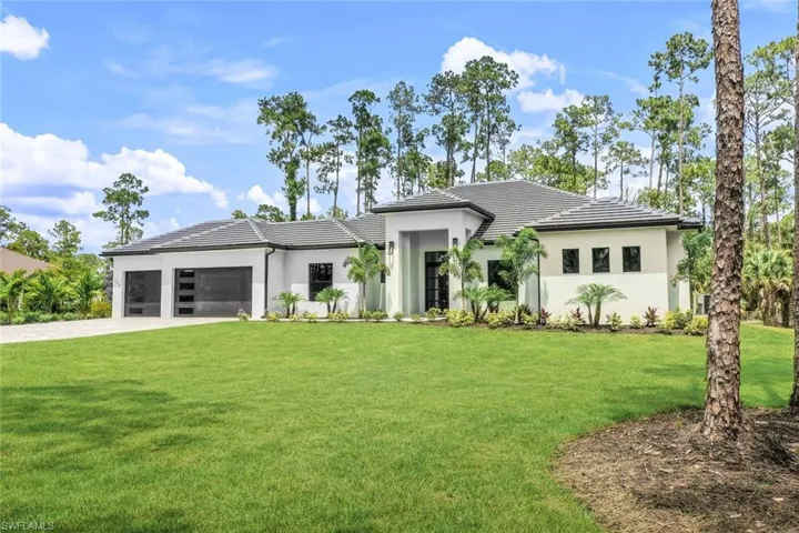 View of front of property with a garage and a front lawn