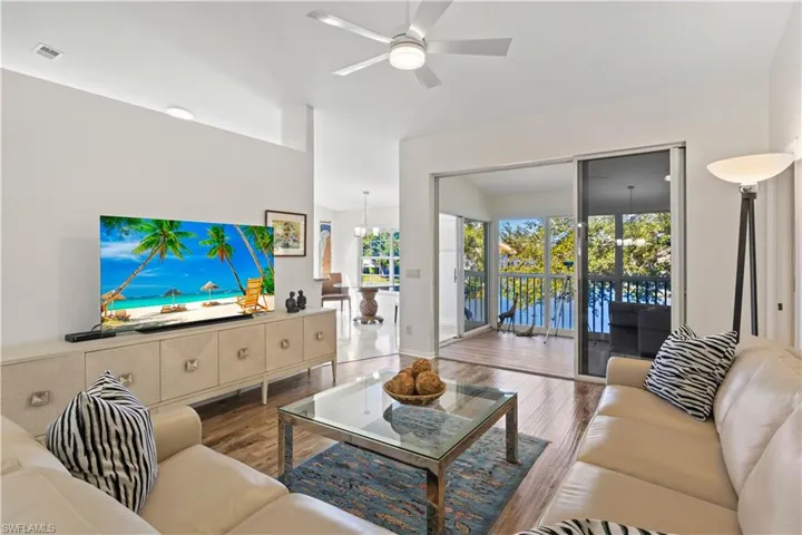 Living room with wood finished floors, ceiling fan, and a chandelier