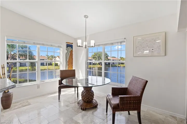 Dining room featuring healthy amount of natural light, lofted ceiling, a water view, and a chandelier