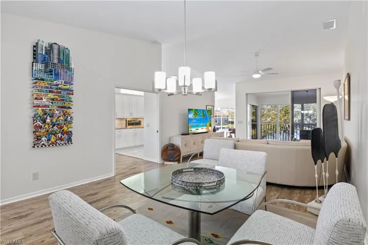 Living area featuring a chandelier, light wood finished floors, a ceiling fan, and high vaulted ceiling