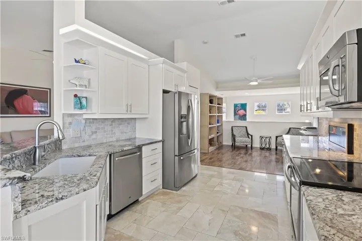 Kitchen featuring ceiling fan, tasteful backsplash, open shelves, white cabinets, and light stone counters
