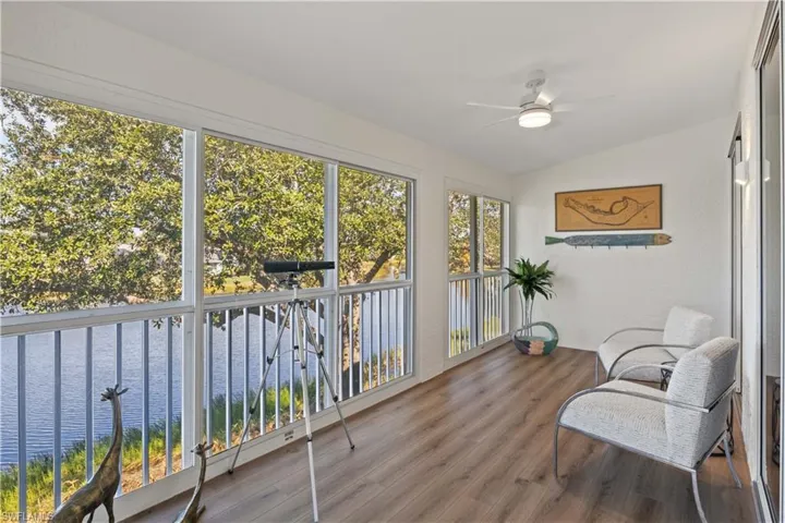 Sunroom / solarium featuring lofted ceiling, wood finished floors, and a textured wall