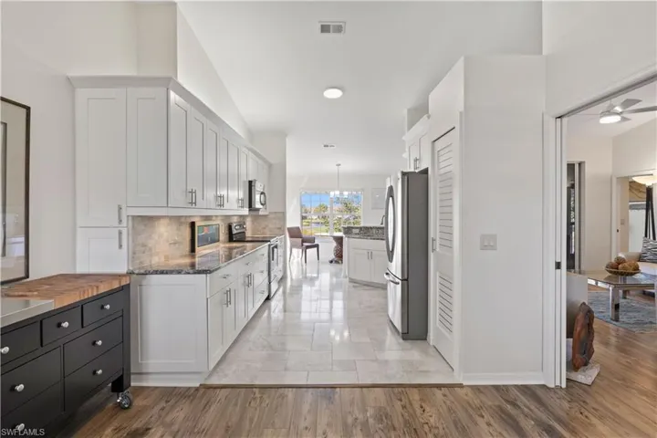 Kitchen with white cabinetry, stainless steel appliances, dark stone countertops, and hanging light fixtures