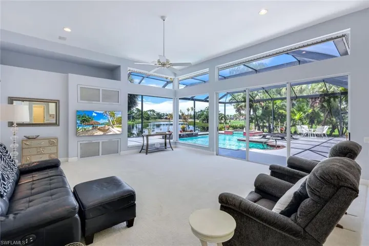 Living room with a healthy amount of sunlight, carpet, ceiling fan, and a high ceiling