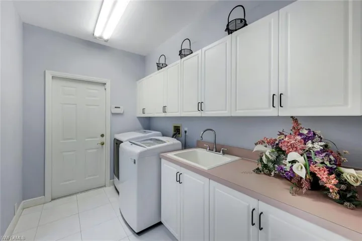 Washroom with cabinets, light tile flooring, washing machine and clothes dryer, hookup for a washing machine, and sink