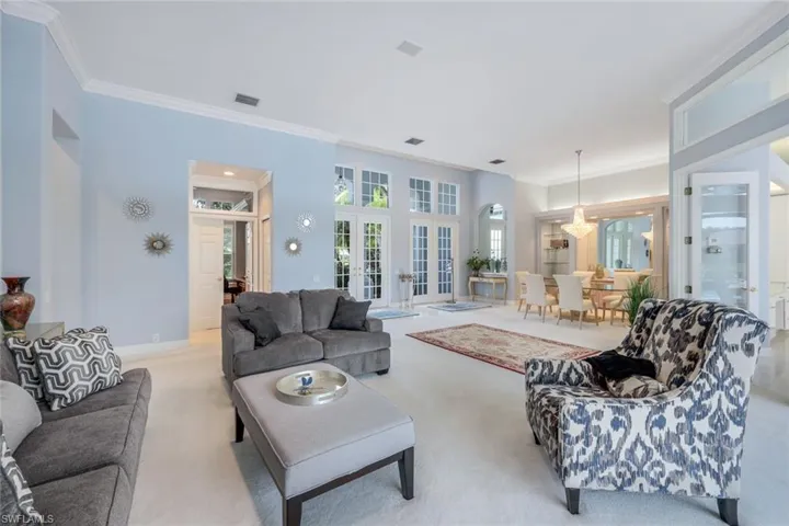 Carpeted living room featuring ornamental molding and french doors