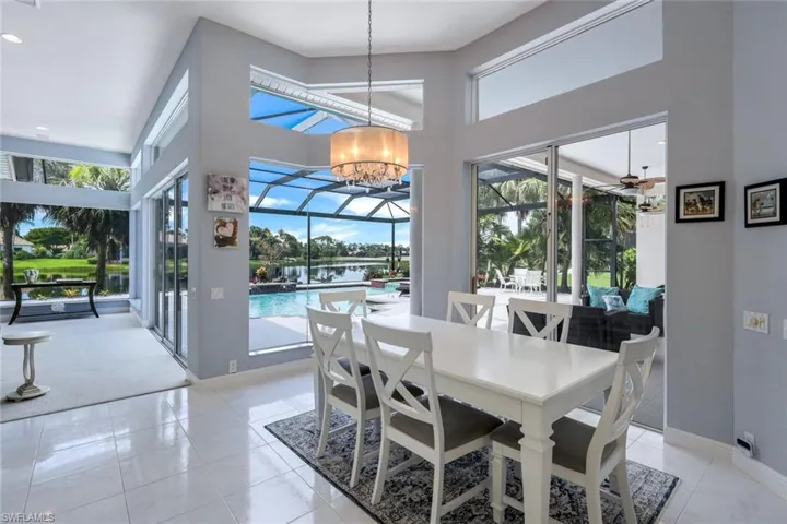 Dining room featuring a towering ceiling, ceiling fan with notable chandelier, and a wealth of natural light