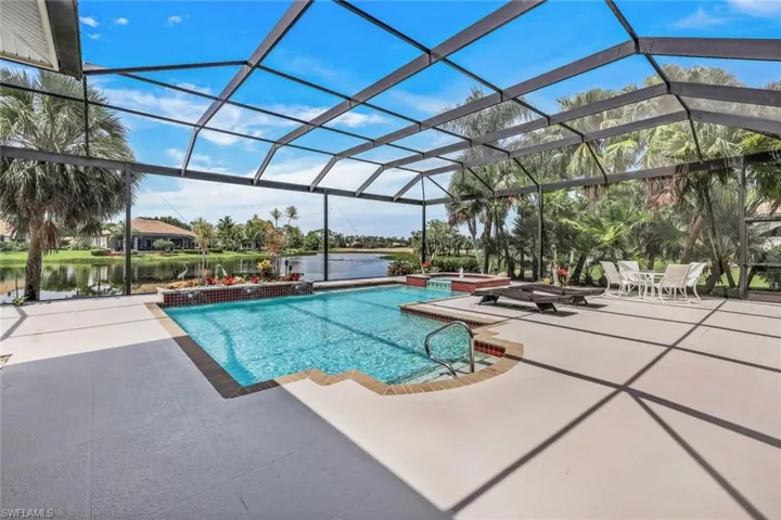 View of swimming pool featuring a patio area, glass enclosure, and a water view