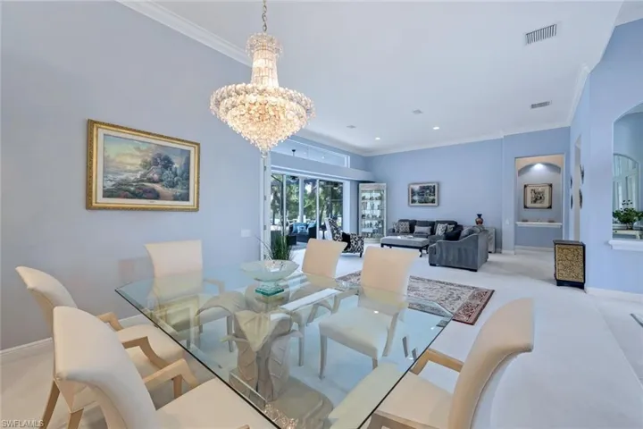 Carpeted dining room featuring an inviting chandelier and crown molding