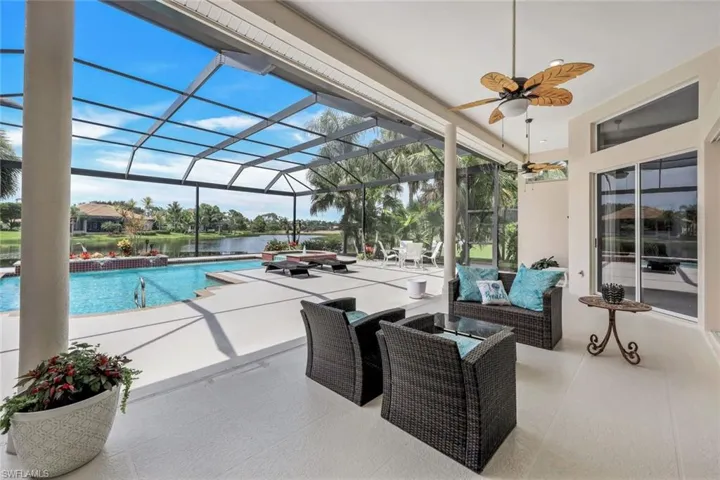 View of pool with ceiling fan, glass enclosure, a patio area, and an outdoor hangout area