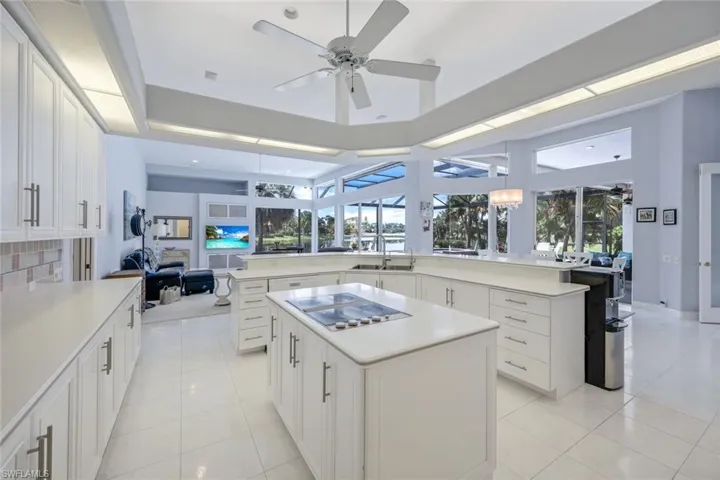 Kitchen featuring ceiling fan, a healthy amount of sunlight, light tile flooring, and a kitchen island