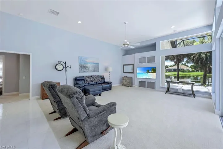 Tiled living room featuring ceiling fan, a towering ceiling, and a water view