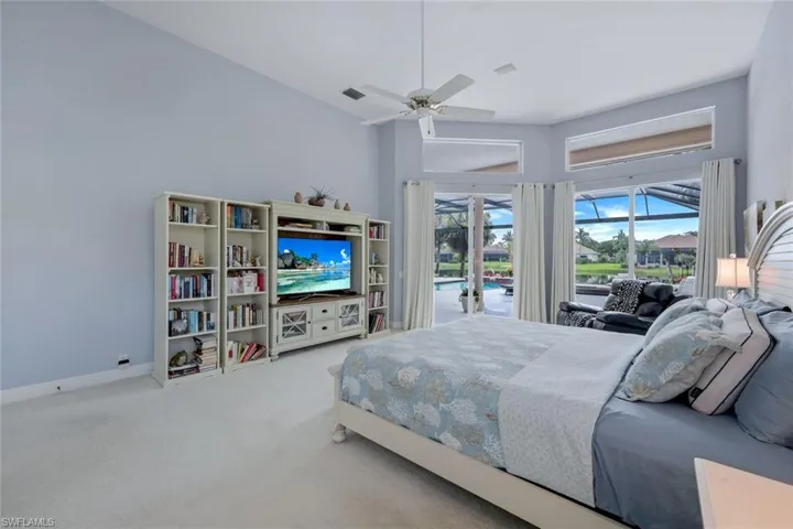 Carpeted bedroom featuring ceiling fan, a towering ceiling, and access to exterior