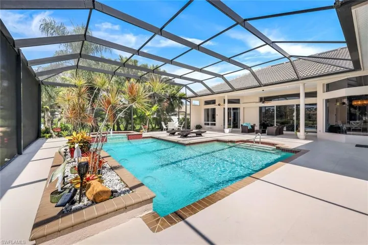 View of pool featuring ceiling fan, an in ground hot tub, glass enclosure, and a patio area